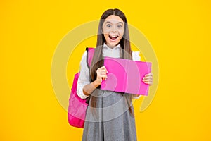 Excited face. Schoolgirl, teenage student girl hold book on yellow isolated studio background. School and education