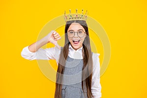 Excited face. Teenage selfish girl celebrates success victory. Teen child in queen crown isolated on yellow background