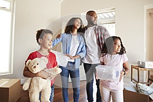 Excited Family Carrying Boxes Into New Home On Moving Day