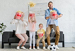 excited family holding boxes and throwing popcorn