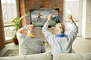 Excited family watching female football, sport match at home, beautiful couple