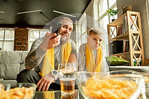 Excited family watching football, sport match at home, father and son