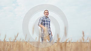 Excited farmer man in the middle of the wheat field happy he waking through the wheat and enjoying the time. Shot on