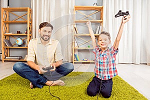 Excited father and son playing video games. happy little boy winning