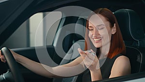 Excited female client buyer happy smiling woman inside new car owner showing keys to camera laughing enjoying buying