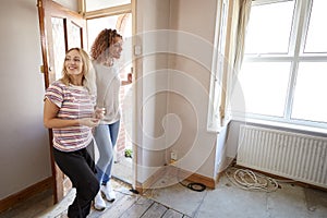 Excited Female Couple Opening Front Door Of New Home