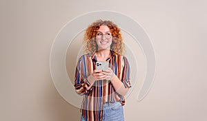 Excited female entrepreneur with curly hair using social media on smart phone over white background