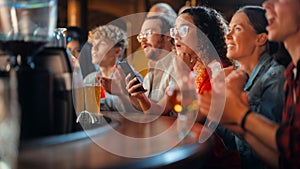 Excited Female Holding a Smartphone, Sitting at a Bar Stand. Nervous About the Sports Bet She Put on