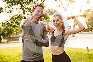 Excited fitness sport loving couple friends showing biceps looking camera.