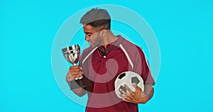 Excited, football and face of a man with a trophy isolated on blue background in studio. Happy, success and portrait of