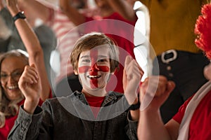 Excited football fans supporting English national team in live soccer match at stadium.