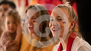 Excited football fans, supporting German national team in live soccer match at stadium.