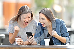 Excited friends celebrating online news on phone