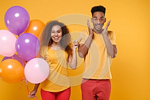 Excited friends couple african american guy girl in casual clothes isolated on yellow background. Birthday holiday party