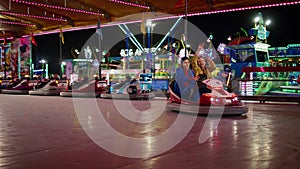 Excited friends driving bumper car in amusement luna park. Happy girls enjoying