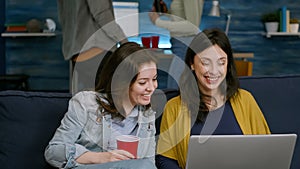 Excited friends watching entertainment show on laptop while sitting on couch