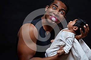 Excited funny cheerful man with a nipple holding his baby