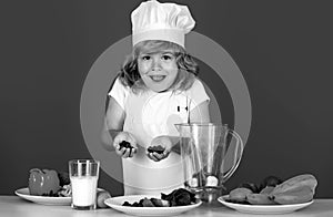 Excited funny chef cook. Child chef dressed cook baker apron and chef hat cooking blueberries smoothie isolated on