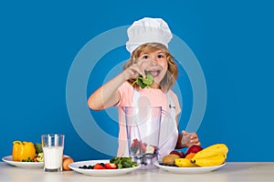 Excited funny chef cook. Kid boy in chef hat and apron hold spinach cooking preparing meal. Little cook with vegetables