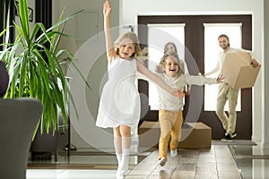 Excited funny kids running inside new house on moving day photo