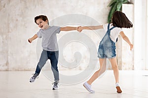 Excited funny kids siblings holding hands spinning playing at home