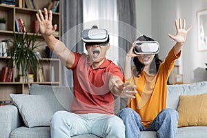 Excited funny korean couple playing video games, using VR glasses