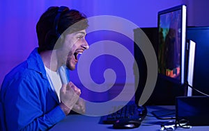 Excited Gamer Winning Computer Game Celebrating Sitting At PC Indoor