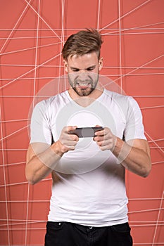 Excited about gaming. Guy play game smartphone gadget. Gamer aggressive face play online game smartphone. Application