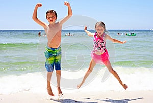 Excited girl and boy jumping together on beach