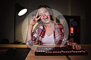 Excited girl gamer sitting at the table, playing online games