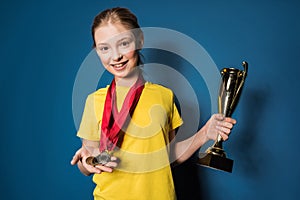 Excited girl with medals and trophy cup