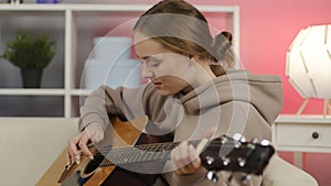 Excited girl playing acoustic guitar in living room.