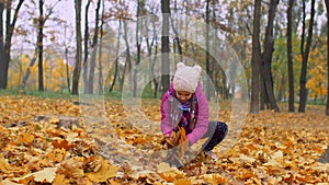 Excited girl throwing fallen autumn foliage in park