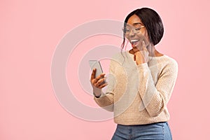 Excited Girl Using Smartphone Holding Finger On Chin, Pink Background