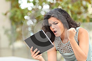 Excited girl watching media content on a tablet in a park