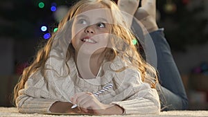 Excited girl writing letter to Santa Claus dreaming about gifts pile, childhood