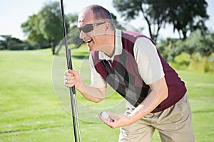 Excited golfer holding ball and club