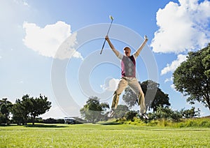 Excited golfer jumping up holding club