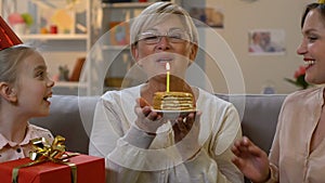 Excited granny receiving presents and cake from family, joy of being together