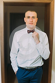 Excited groom posing standing in doorcase of hotel room