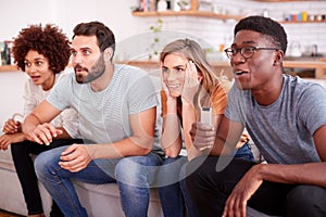 Excited Group Of Friends Sitting On Sofa And Watching Sports On TV