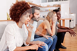 Excited Group Of Friends Sitting On Sofa And Watching Sports On TV