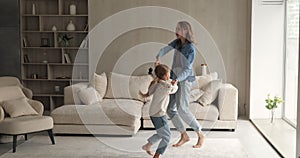 Excited grown elder preteen younger sisters dance at living room