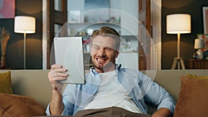 Excited guy achieving pad computer at house zoom on. Satisfied man saying wow