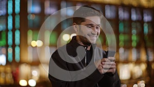 Excited guy messaging mobile phone on street. Cheerful man using phone outdoors.