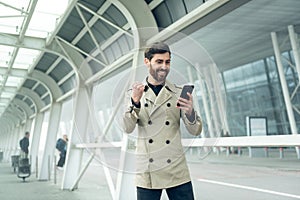 Excited handsome businessman cheering while receiving good news on phone