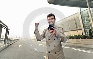 Excited handsome guy cheering while receiving good news on phone