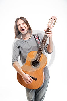 Excited handsome young man with long hair playing acoustic guitar