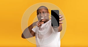 Excited happy adult african american man showing smartphone with blank screen to camera