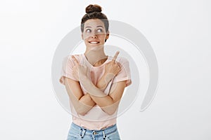 Excited and happy attractive woman with hairbun in t-shirt biting lower lip in anticipation and interest making choice